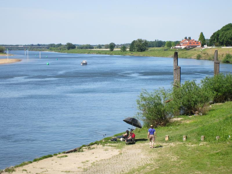 Zwei Angler mit Ruten an einem breiten Flussufer