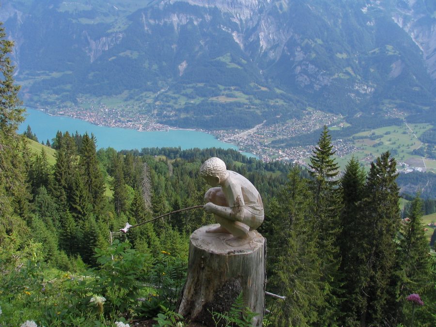Geschnitzte Holzfigur auf dem Schnitzlerweg der Axalp mit Brienz im Hintergrund