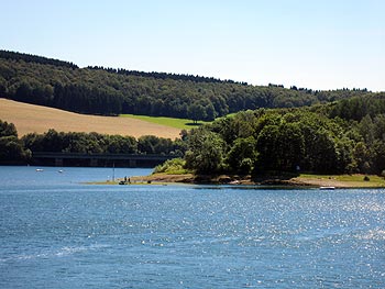 Biggesee mit bewaldetem Ufer und Brücke
